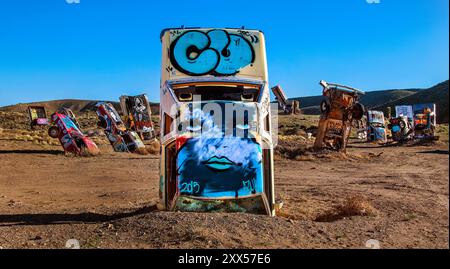 Fahrzeuge sind teilweise begraben und bemalt, unter anderem über den International Car Forest of the Last Church in Goldfield, Nevada. Stockfoto