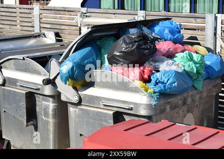 Müllbeutel aus Kunststoff in einem vollen Behälter aus Metall Stockfoto