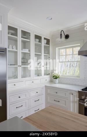 Ecke der weißen Küche mit Geschirr hinter Glasschränken Stockfoto