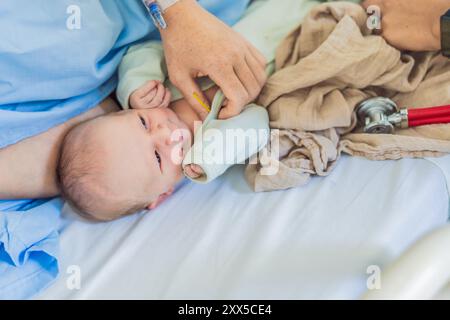 Eine Krankenschwester misst die Temperatur eines Babys im Krankenhaus. Das sanfte und sorgfältige Verfahren sorgt für Komfort und Wohlbefinden des Babys, was es ermöglicht Stockfoto