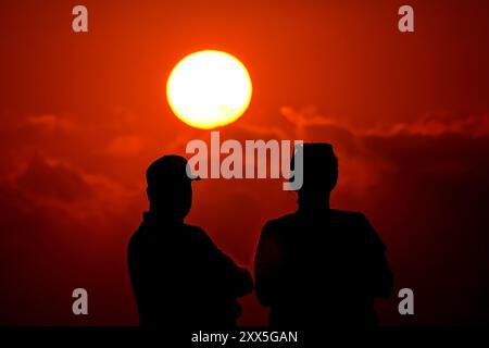 Isle Of Palms, Usa. August 2024. Strandbesucher beobachten, wie die Sonne bei Sonnenaufgang am Strand von Wild Dunes, 21. August 2024 in Isle of Palms, South Carolina, über eine Sturmwolke blickt. Quelle: Richard Ellis/Richard Ellis/Alamy Live News Stockfoto