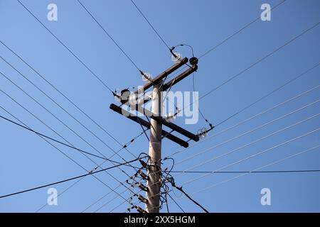 Hochspannungsdrähte am Pol, dreiphasige Nahaufnahme auf blauem Himmel Hintergrund Stockfoto