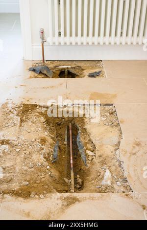 Heizungsleitungen für Haushalte, die unter einem Fliesenboden freiliegen, nachdem ein Wasserleck in einem britischen Haus repariert wurde Stockfoto