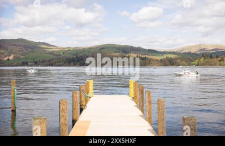 Lake Windermere mit Holzsteg und Booten an einem sonnigen Tag in Lake District, Cumbria, Großbritannien Stockfoto