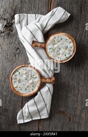 Flache Liege mit zwei Schüsseln hausgemachter Clam Chowder Schüsseln auf einem rustikalen Holztisch mit Küchentuch. Stockfoto