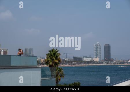 Barcelona, Spanien. August 2024. Von der Terrasse des W Barcelona Hotels aus sieht man eine Person, die die Regatta mit einem Fernglas beobachtet. Die Louis Vuitton Preliminary Regatta 2024 America's Cup hat heute Morgen die ersten Vorläufe gestartet. Besucher, Touristen und Einwohner konnten das erste Rennen des Wettbewerbs kostenlos von den Aussichtspunkten an der Küste und auf großen Bildschirmen in den Fan Zones genießen. Quelle: SOPA Images Limited/Alamy Live News Stockfoto