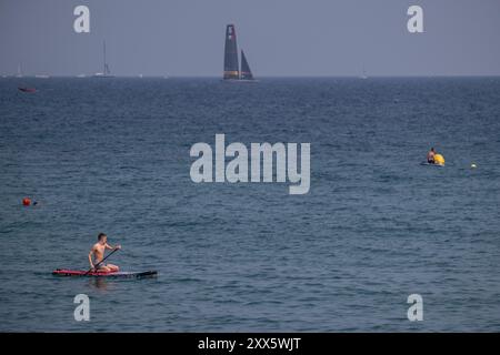 Barcelona, Spanien. August 2024. Nach dem Copa America-Wettbewerb wird ein Schwimmer auf einem Surfbrett gesehen. Der Louis Vuitton Preliminary Regatta 2024 America's Cup hat heute Morgen die ersten Vorläufe gestartet. Besucher, Touristen und Einwohner konnten das erste Rennen des Wettbewerbs kostenlos von den Aussichtspunkten an der Küste und auf großen Bildschirmen in den Fan Zones genießen. (Foto: Paco Freire/SOPA Images/SIPA USA) Credit: SIPA USA/Alamy Live News Stockfoto