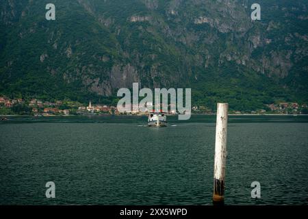 Mandello del Lario, Italien - 08. Juni 2024: Ein Boot fährt direkt in die Kamera. Wunderschöne Berge im Hintergrund. Como See im Vordergrund. Stockfoto