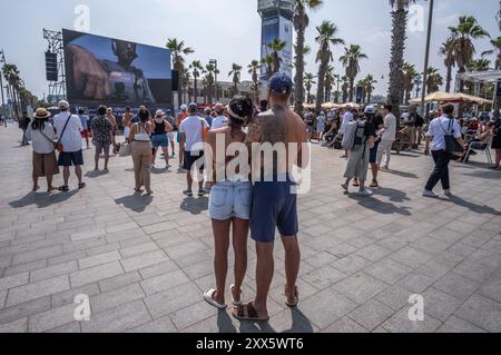 Barcelona, Spanien. August 2024. Eine Gruppe von Menschen wird auf dem Plac del Mar beobachtet, die den Regatten auf einer riesigen Leinwand folgen. Die Louis Vuitton Preliminary Regatta 2024 America's Cup hat heute Morgen die ersten Vorläufe gestartet. Besucher, Touristen und Einwohner konnten das erste Rennen des Wettbewerbs kostenlos von den Aussichtspunkten an der Küste und auf großen Bildschirmen in den Fan Zones genießen. (Foto: Paco Freire/SOPA Images/SIPA USA) Credit: SIPA USA/Alamy Live News Stockfoto