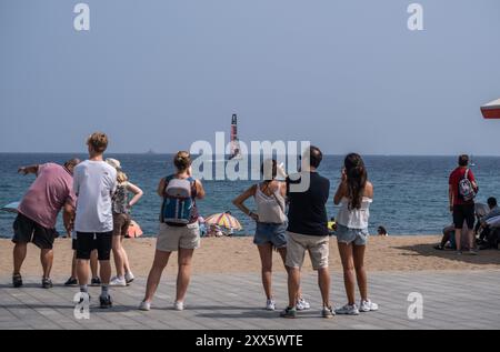 Barcelona, Spanien. August 2024. Eine Gruppe von Kinderwagen am Strand ist von der Nähe eines der America's Cup Segelboote überrascht. Die Louis Vuitton Preliminary Regatta 2024 America's Cup hat heute Morgen die ersten Vorläufe gestartet. Besucher, Touristen und Einwohner konnten das erste Rennen des Wettbewerbs kostenlos von den Aussichtspunkten an der Küste und auf großen Bildschirmen in den Fan Zones genießen. (Foto: Paco Freire/SOPA Images/SIPA USA) Credit: SIPA USA/Alamy Live News Stockfoto