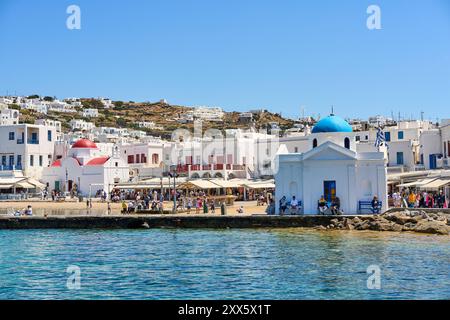 Mykonos, Griechenland - 7. Mai 2024: Eine Kapelle mit blauem Dach an der Küste von Mykonos, Griechenland, umgeben von typischen weiß getünchten Gebäuden in der Altstadt *** eine Kapelle mit blauem Dach an der Küste von Mykonos, Griechenland, umgeben von typischen weiß getünchten Gebäuden in der Altstadt Stockfoto