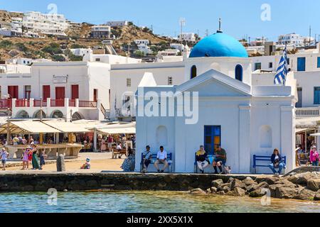 Mykonos, Griechenland - 7. Mai 2024: Eine Kapelle mit blauem Dach an der Küste von Mykonos, Griechenland, umgeben von typischen weiß getünchten Gebäuden in der Altstadt *** eine Kapelle mit blauem Dach an der Küste von Mykonos, Griechenland, umgeben von typischen weiß getünchten Gebäuden in der Altstadt Stockfoto