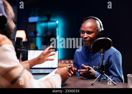 Der Moderator der Black man-Radiosendung hält Live-Chat mit Gästen und zeichnet die Interaktion auf, damit das Publikum live hören kann. Influencer spricht mit Journalisten und sendet die Debatte an Online-Fans zu Hause. Stockfoto