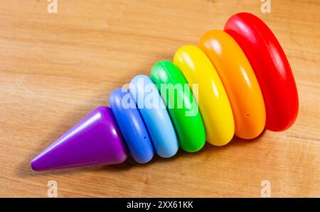 Regenbogenplastik-Stapelturm-Spielzeug für Kleinkinder auf Holzoberfläche Stockfoto