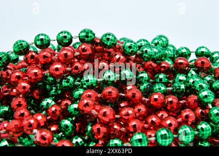 Nahaufnahme, detailliert, Makroaufnahme von roten, grünen Weihnachtsdiscokugeln, Halskette, Baumdekoration Design auf weißem Hintergrund. Stockfoto