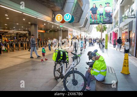 Uber Eats Lieferfahrer machen eine Pause neben Sydney Chatswood Transportstation und Umsteigepunkt, Sydney, NSW, Australien Stockfoto