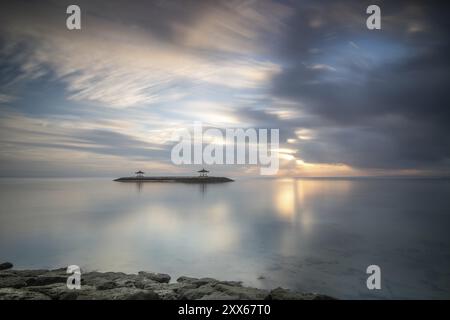 Wunderschöne Meereslandschaft am Morgen. Tropischer Sandstrand mit Wellenbrecher und Reflektion des Himmels im ruhigen Wasser. Morgenlandschaft, aufgenommen in Sanur Stockfoto