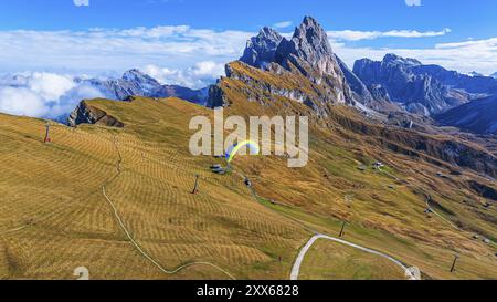 Gleitschirmfliegen über alpine Wiesen, im Hintergrund die Gipfel SAS Rigais und Furchetta der Geißler Gruppe, Drohnenschuss, Gröden, Dolomiten, autonom Stockfoto