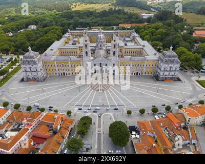 Historischer Palast in beeindruckender Symmetrie als Luftaufnahme, umgeben von grüner Vegetation, Luftaufnahme, Palast, Palacio Nacional de Mafra, Stockfoto