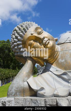 Nahaufnahme einer liegenden Buddha-Statue, die meditative Ruhe vor einem klaren blauen Himmel ausstrahlt, Bacalhoa, Bacalhoa Buddha Eden, Quinta dos Loridos, größte Stockfoto