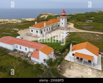 Aus der Vogelperspektive auf einen Leuchtturm und benachbarte Gebäude an der Küste mit orangefarbenen Dächern, Farol do Cabo Sardao, Sardao, Ponta do Cavaleiro, Odemira Stockfoto