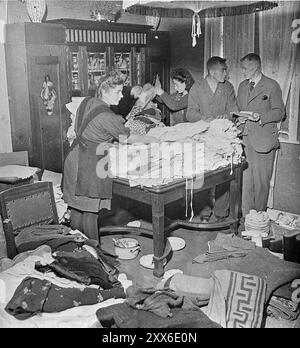 Ilse Kohra(L), Tochter des Burgermeisters der deutschen Stadt Belsen, sortierte zusammen mit Herrn Pfeifer(R) und seiner Tochter Anna im Haus des Burgermeisters Kleidung für die Überlebenden Bergen-Belsens. Stockfoto