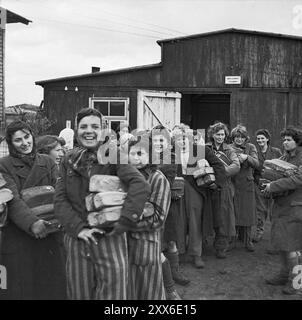 Glückliche Überlebende des Konzentrationslagers Bergen-Belsen lächeln nach ihrer Befreiung. Sie alle halten Brotlaibe fest. Die Lage des Lagers im Westen Deutschlands bedeutete, dass Tausende von Menschen dorthin geschickt wurden, als der Osten fiel. 18000 Menschen starben allein im März 1945, 10000 starben in den zwei Wochen nach der Befreiung. Sie starben eher an Krankheiten und Vernachlässigung als an systematischen Misshandlungen, wie sie anderswo zu beobachten waren. Stockfoto