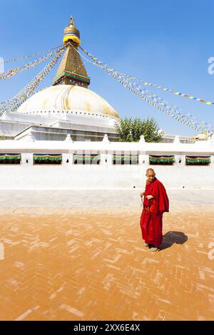 Kathmandu, Nepal, 18. Oktober 2013: Buddhistischer Mönch in rotem Gewand, der Gebetsperlen auf Bodenhöhe von Boudhanath Stupa trägt, an sonnigen Tagen in Asien Stockfoto