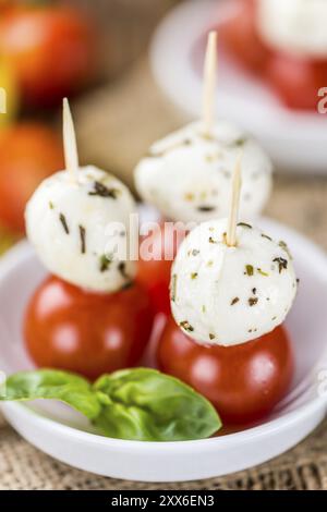 Tomaten und Mozzarella mit frischem Basilikum (Tiefenschärfe) auf einem alten Holztisch Stockfoto