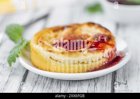 Mini-Käsekuchen (mit Soße) als hoch detaillierte Nahaufnahme auf einem Vintage Holztisch (Tiefenschärfe) Stockfoto