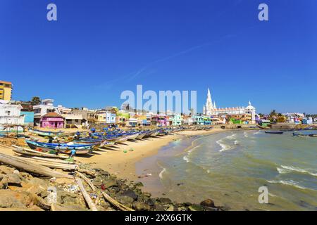 Kanyakumari, Indien, 22. Februar 2015: Die Kirche der Our Lady of Ransom Shrine hinter bunten Häusern an einem Sandstrand, der von Fischerbooten in Tamil Nadu besetzt ist Stockfoto