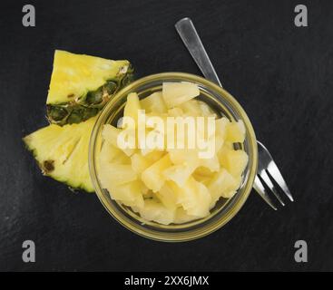 Teil der konservierten Ananas (gehackt) als detaillierte Nahaufnahme auf einer Schieferplatte, selektiver Fokus Stockfoto