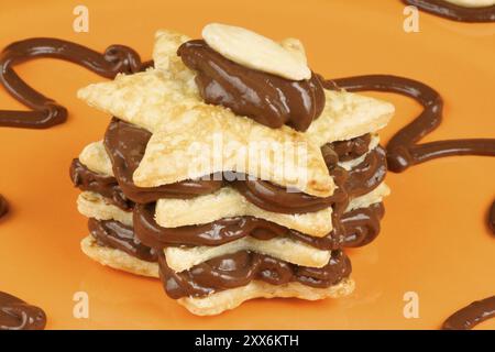 Sternförmige Schokoladencreme und Mandel-Millefeuille auf einem Orangenteller. Selektiver Fokus Stockfoto