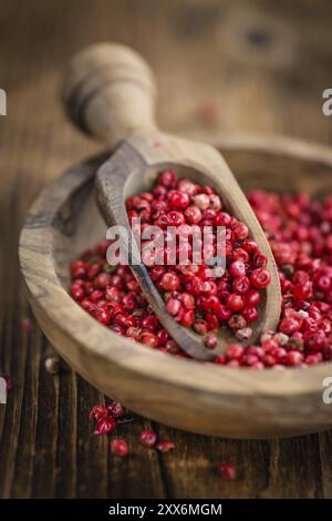 Rosa Pfeffer als detailreiche Nahaufnahme auf einem Vintage Holztisch, selektiver Fokus Stockfoto