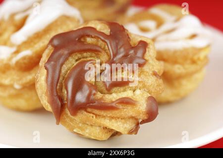 Zeppole di San Giuseppe oder St. Joseph's Day Cream Puffs, sind süditalienische, frittierte Kuchen, gefüllt mit Pudding und Frosted. Isoliert auf Rot Stockfoto