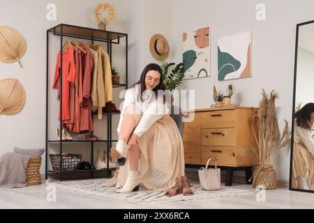 Junge Frau, die zu Hause Stiefel anzieht Stockfoto