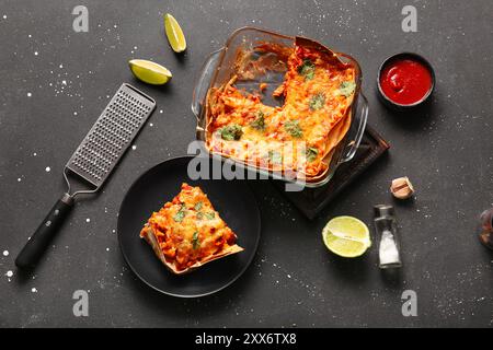 Komposition mit leckerer Enchilada, Gewürzen und Tomatensauce auf dunklem Hintergrund Stockfoto