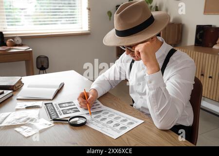 Männlicher Detective mit Fingerabdrücken, der den Fall am Tisch im Büro untersucht Stockfoto