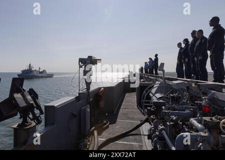 NORFOLK, Virginia (22. August 2024) Seeleute an Bord des Flugdecks des größten Flugzeugträgers der Welt, USS Gerald R. Ford (CVN 78), bemannen die Schienen, während das Amphibious Transport Dock Schiff USS Fort Lauderdale (LPD 28) der San Antonio-Klasse beim Durchqueren der Chesapeake Bay am 22. August 2024 Auszeichnungen ausgibt. Die USS Gerald R. Ford (CVN 78) ist das Flaggschiff der Gerald R. Ford Carrier Strike Group. Der Flugzeugträger ist im Atlantik unterwegs, um während seiner Grundphase des optimierten flottenreaktionssystems (pla) Kernkompetenzen und Fähigkeiten der Kerneinheiten wie Treibstoffzertifizierung und Munition on load weiter zu entwickeln Stockfoto