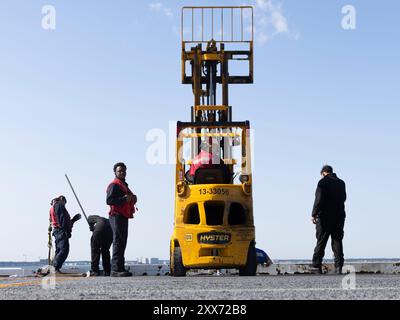 NORFOLK, Virginia (22. August 2024) Seeleute, die an Bord des größten Flugzeugträgers der Welt, USS Gerald R. Ford (CVN 78), dem Luftministerium zugeteilt sind, setzen mit einem Gabelstapler die Coaming-Sicherheitsnetze des Flugdecks ein, 22. August 2024. Die USS Gerald R. Ford (CVN 78) ist das Flaggschiff der Gerald R. Ford Carrier Strike Group. Der Flugzeugträger ist im Atlantik unterwegs, um während seiner Grundphase des optimierten Flottenreaktionsplans Kernkompetenzen und -Fertigkeiten wie die Zertifizierung von Treibstoffen und das Aufladen von Munition weiterzuentwickeln. (Foto der US Navy von Seaman Tajh Payne, Spezialist für Massenkommunikation) Stockfoto