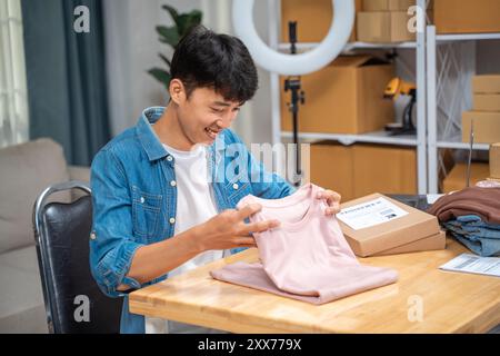 Junger Online-Verkäufer faltet sein Hemdprodukt, bevor er es in den Karton packt, um es an seinen Kunden zu versenden Stockfoto