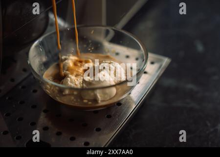 Kaffee aus einer Kaffeemaschine auf Eis in einem Glasbehälter gießen. Stockfoto