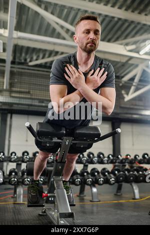 Niedrigwinkelschuss eines männlichen Athleten, der Hyperextension macht, um die Muskeln zu gewinnen Stockfoto