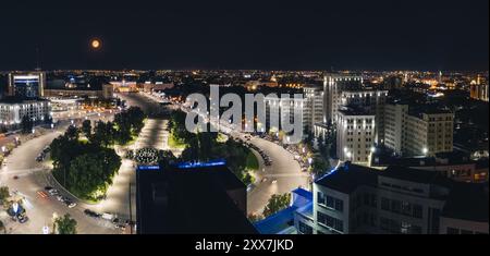 Nächtliches Panorama aus der Luft vom Derzhprom-Gebäude auf dem Freiheitsplatz in der beleuchteten Stadt Charkiw mit Vollmond, Ukraine Stockfoto