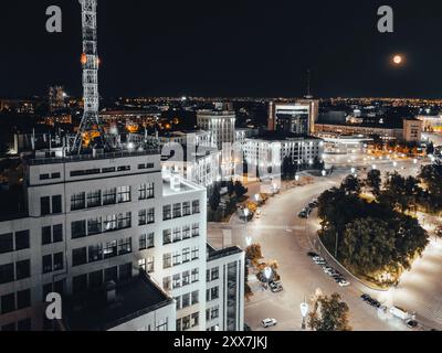 Nächtlicher Luftblick vom Derzhprom-Gebäude auf dem Freiheitsplatz in der beleuchteten Stadt Charkiw, Ukraine Stockfoto
