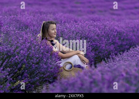 Eine Frau sitzt auf einem Feld aus violetten Blumen Stockfoto