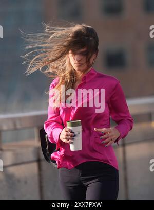 Menschen, die bei windigem Wetter auf der London Bridge laufen, wenn der Sturm Lilian das Vereinigte Königreich trifft. Bilddatum: Freitag, 23. August 2024. Stockfoto