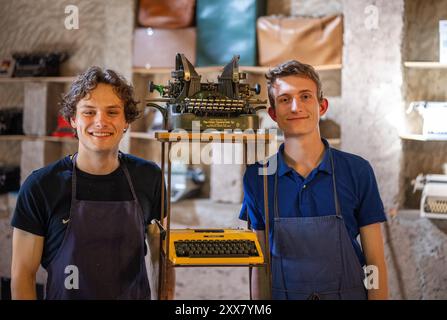 Wiltingen, Deutschland. August 2024. Die Studenten Jakob Kramp (r) und Paul Hallmanns stehen in ihrer Schreibmaschinenwerkstatt. Ob Remington, Underwood, Olivetti, Olympia, Hermes, Continental, Mercedes, Adler oder Erika – sie sammeln, reparieren und verkaufen mechanische Schreibmaschinen aus und auf der ganzen Welt. (Zu dpa Text: Zwei junge Männer sind Schreibmaschinenfans) Credit: Harald Tittel/dpa/Alamy Live News Stockfoto