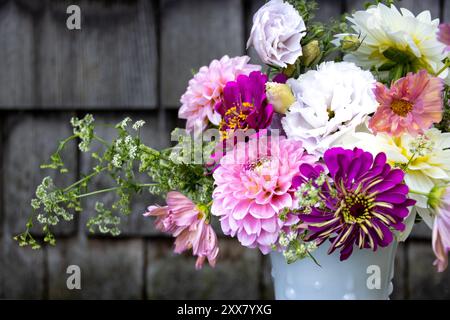 Lebhafter Blumenstrauß in weißer Vase mit Holzhintergrund Stockfoto
