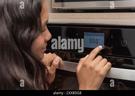 Nahaufnahme Teenager, der die Temperatur im digitalen Ofen einstellt. Stockfoto